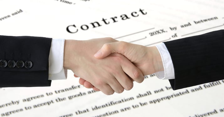 A photo of two people shaking hands with an image of a contract behind them