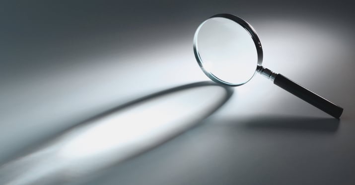 A photo of a magnifying glass laying on its side on a white flat surface