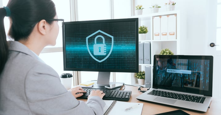 Woman at computer with a graphic of a padlock on computer screen in front of her